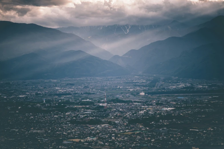 a city in the middle of mountains under a stormy sky