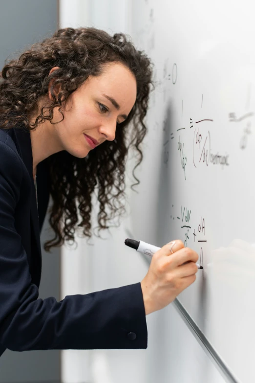 a beautiful young lady writing on a whiteboard