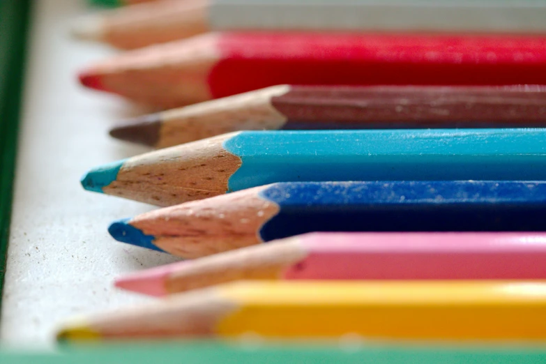 many colored pencils sitting next to each other