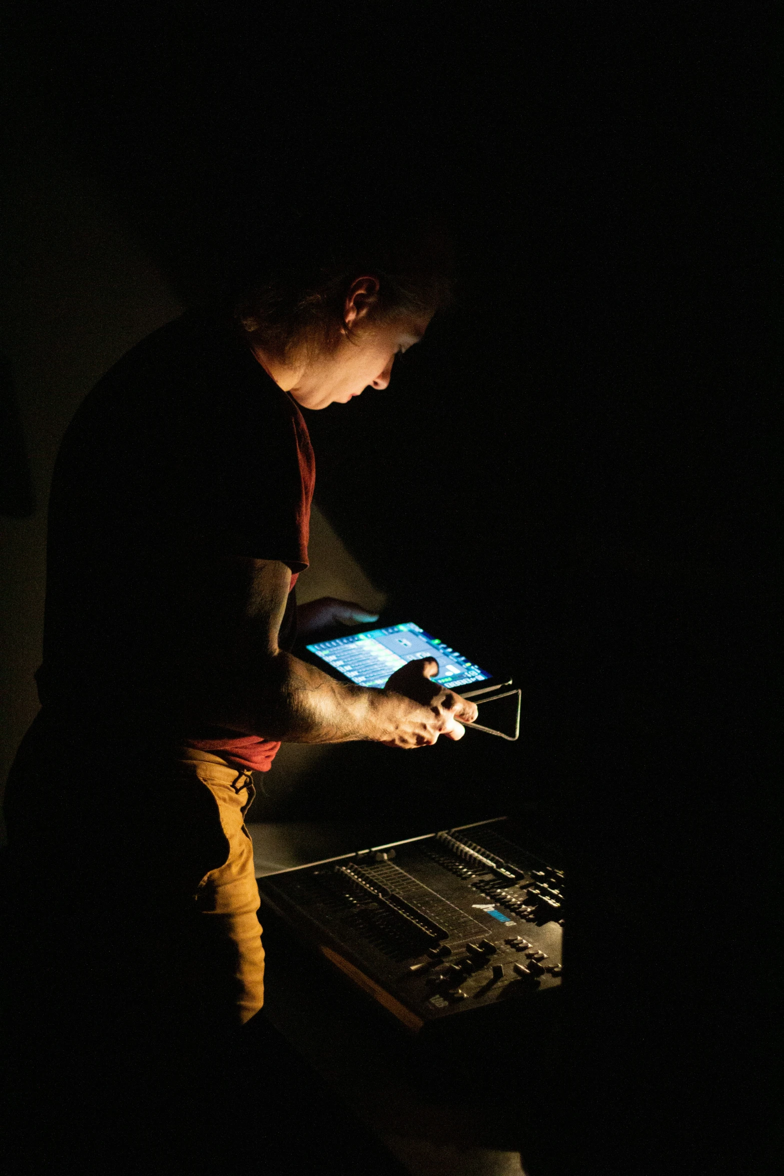 man in dark holding electronic device at table