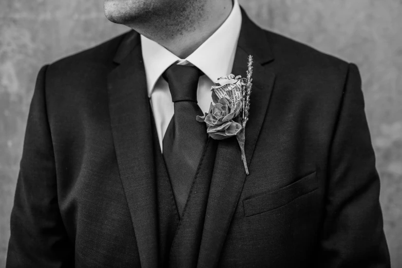 a man in a suit and tie wearing a flower pin