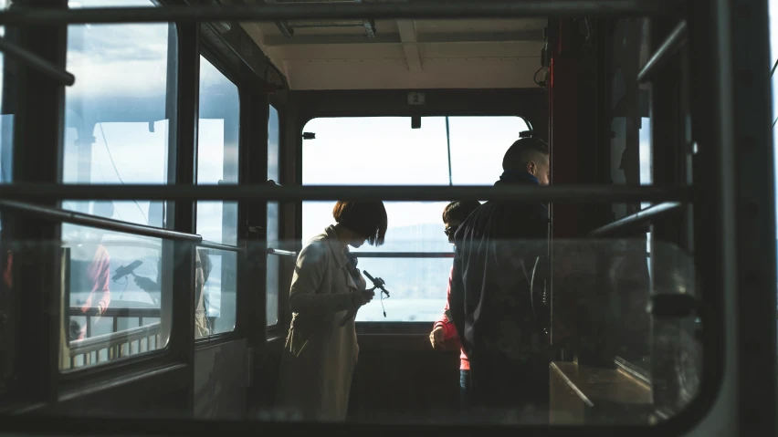 people standing by the window looking out at the ocean