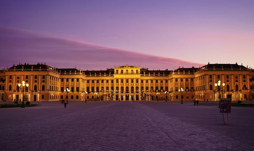 a large building in a plaza with lights on