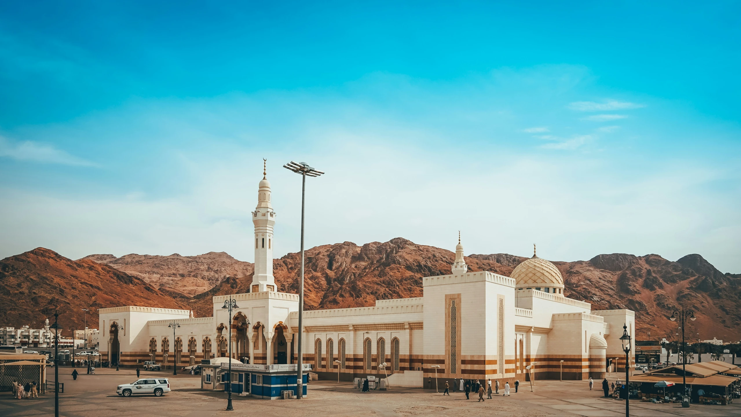 a city square in a desert with a large white building with three towers