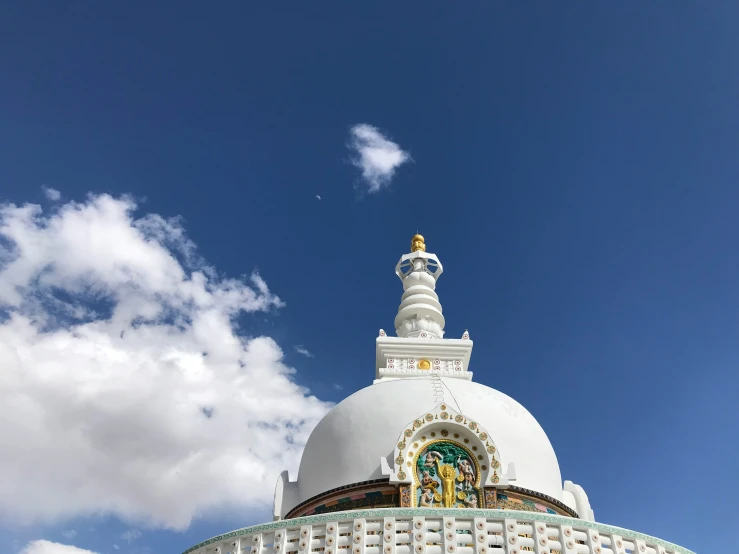 the spire of a white temple with a blue sky in background