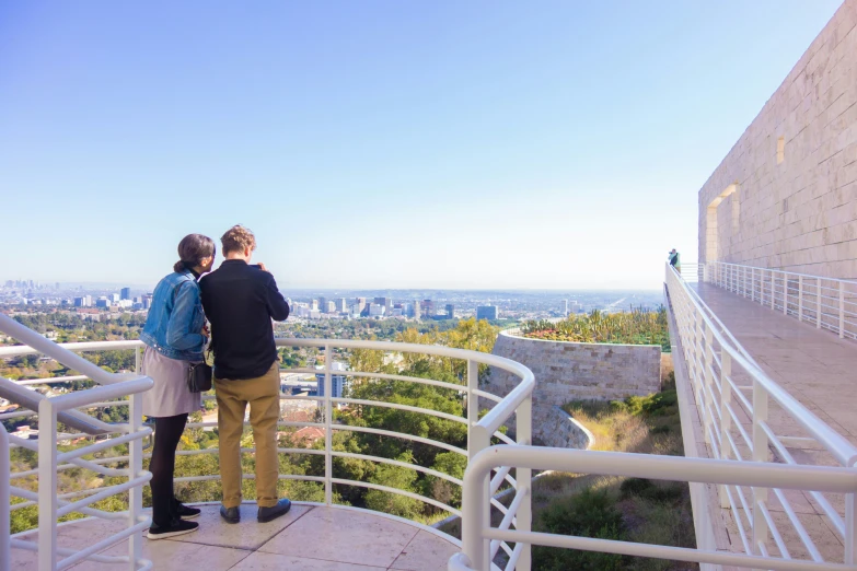 two people stand on the railing of a tall building