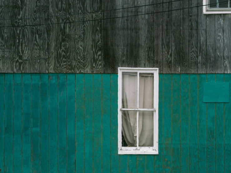 a window against a green and black wooden wall