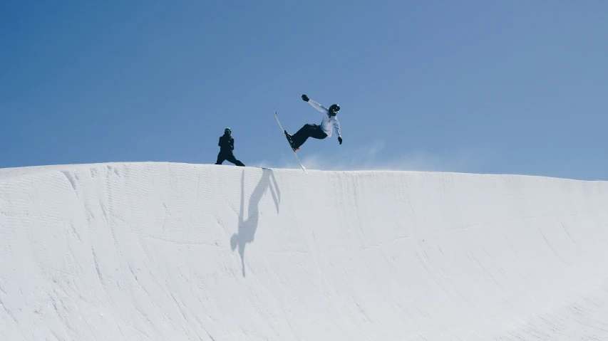 two people are snowboarding down a steep hill