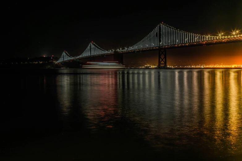 the night lights glow from a large bridge over water