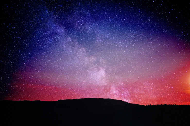 the view from a hill at night looking across the milky