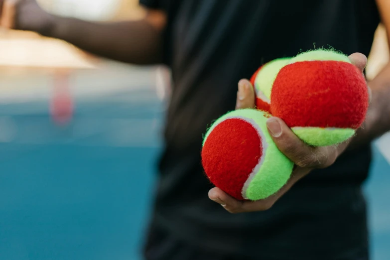 a person holding two tennis balls in their hand