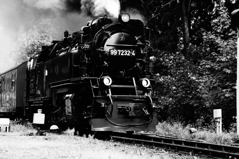 a train traveling down train tracks with steam coming out of the engine