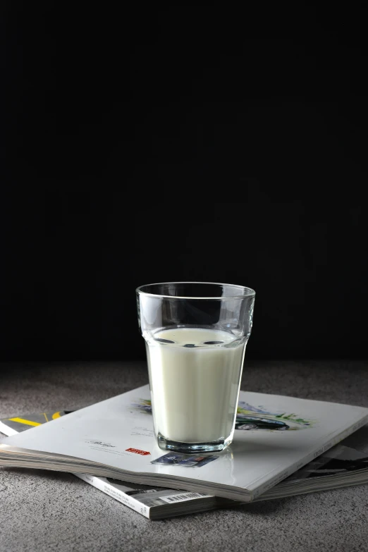 a glass of milk sitting on top of two magazines