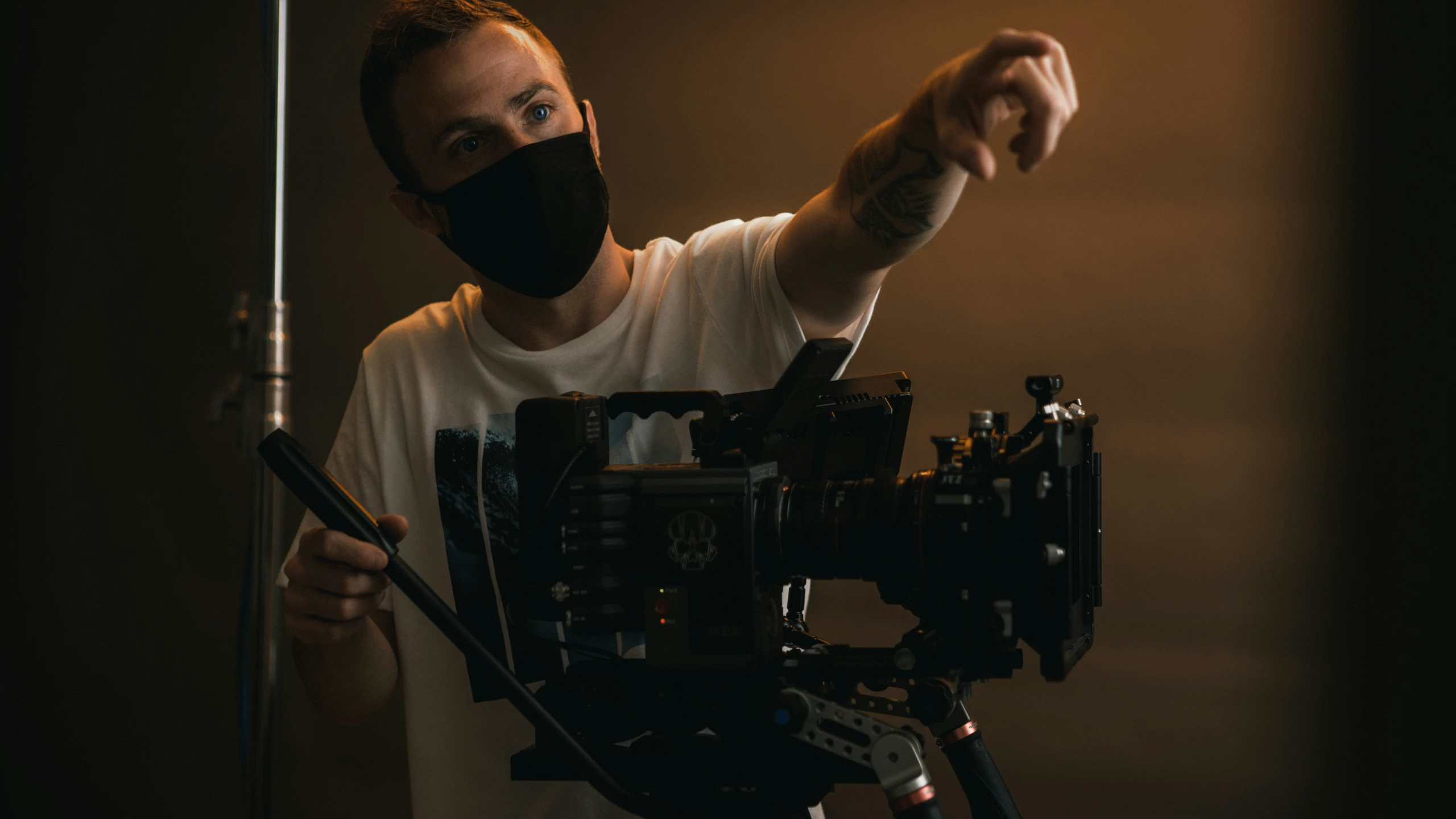 a man is holding a camera and wearing a black face mask