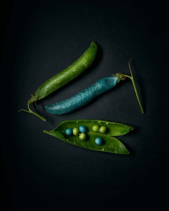 two peas are sitting side by side on top of a green pea leaf