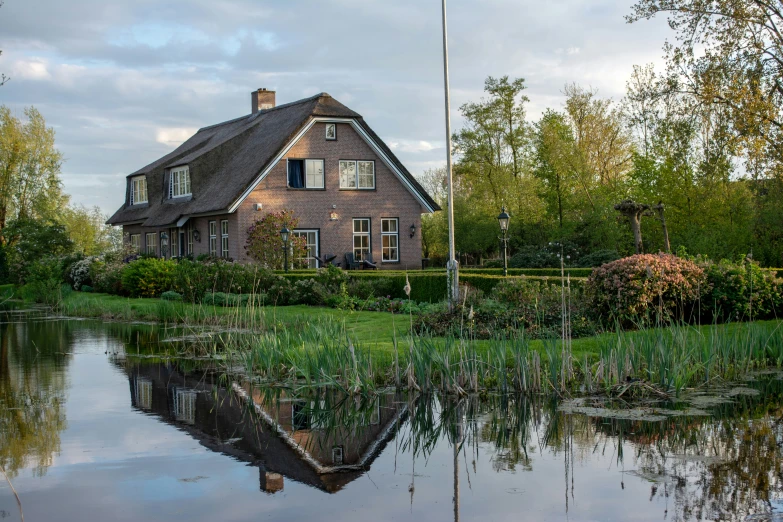 a house is on a lake surrounded by greenery