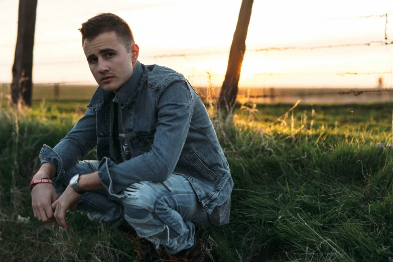 the young man in the denim jacket is posing for the camera