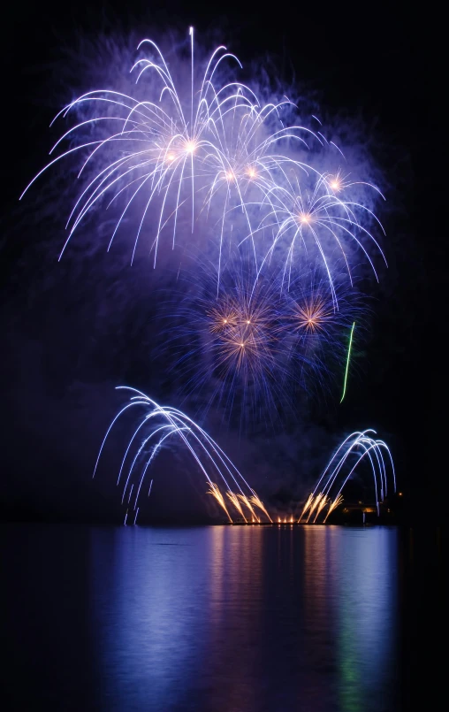 a firework displays some colorful lights and is reflected in the water