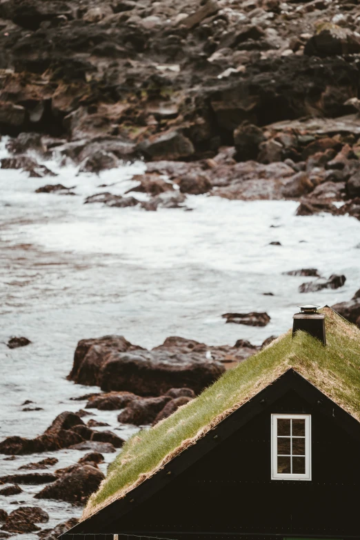 small hut with grass roof overlooking large river and rocky shoreline