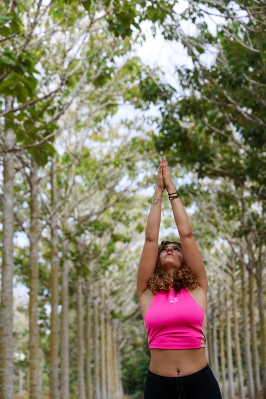 woman standing in front of trees raising her hands to get air