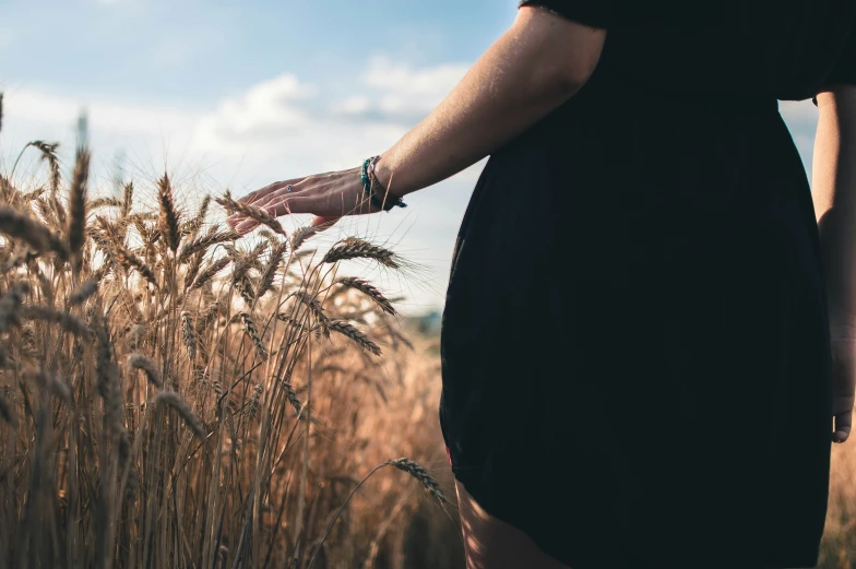 a person with their hands on a tall grass field