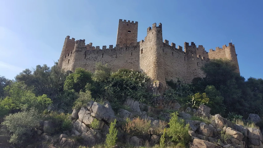 a tall castle building sitting on top of a rocky hillside