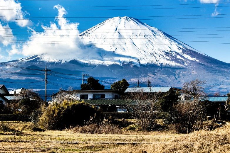 the landscape shows mountains and houses, a fence, and telephone wires