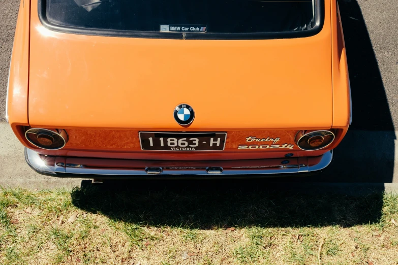 an orange bmw car is parked on the side of the road