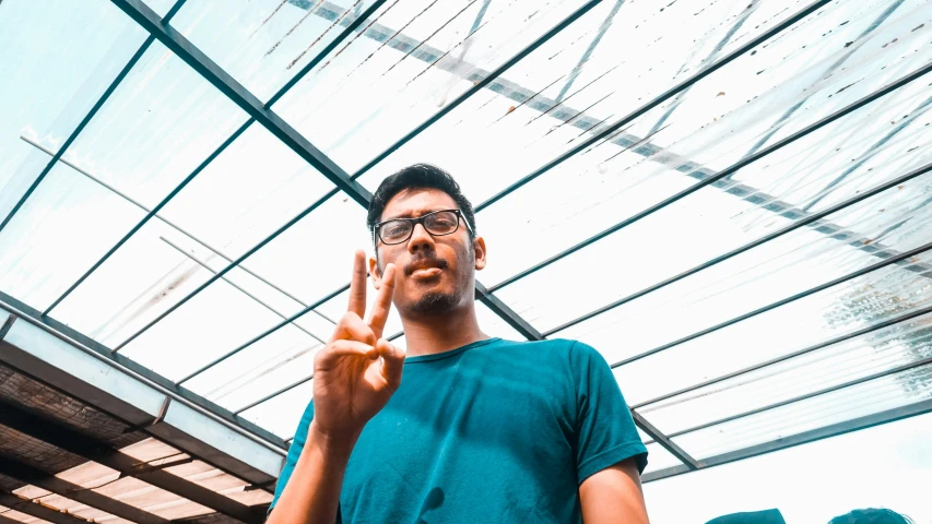 man in blue t - shirt holding a peace sign