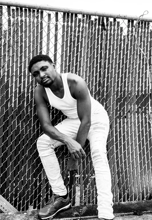 a black and white pograph of a person sitting on a fence