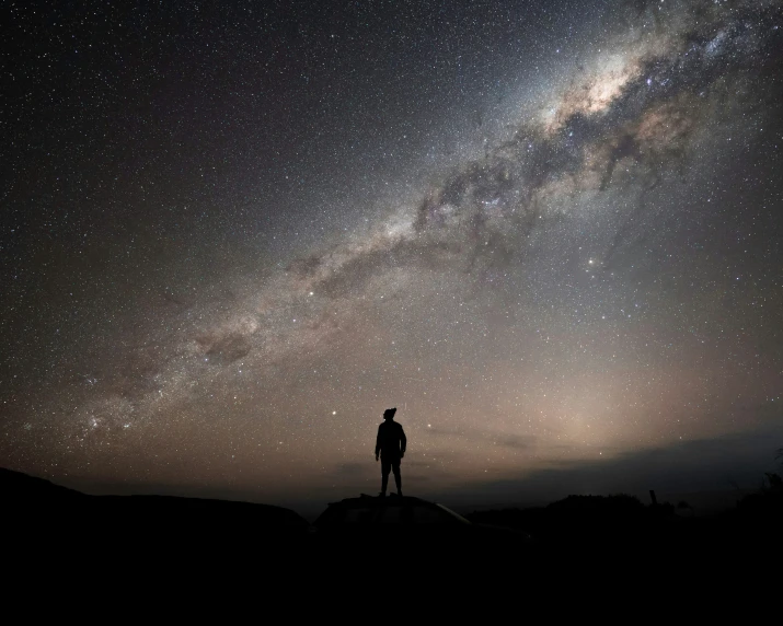 the silhouette of a person standing under a night sky with a bright star