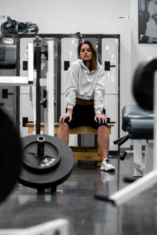 woman sitting on bench in a gym doing cross - training