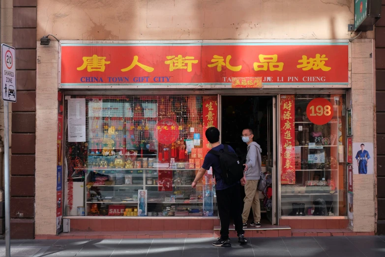 two people are outside of a store on a city street