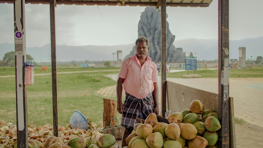 man standing under shade at roadside fruit stand