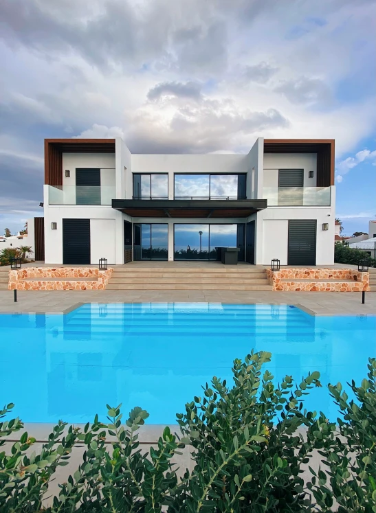 a pool area with an outdoor lounge and large house