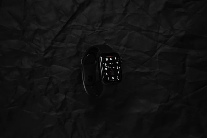 a cellphone lying on a black surface next to an apple watch