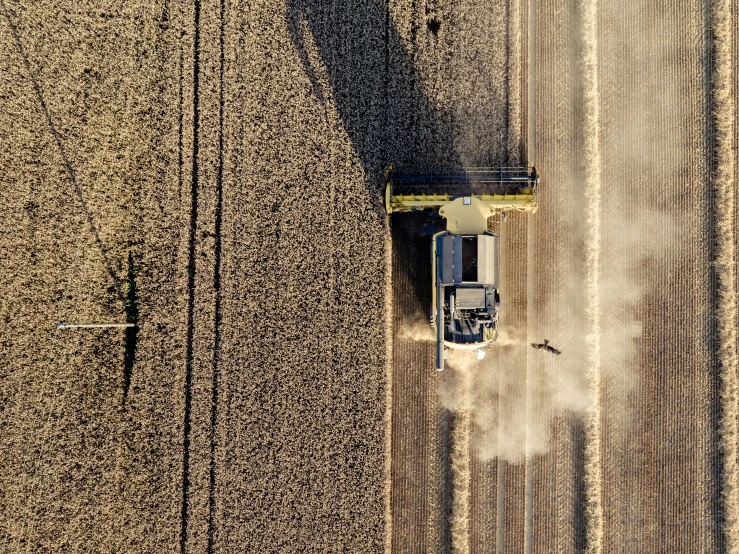 a large tractor is plowing the field with a dust spreader