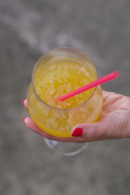 a person holding a glass of juice next to two red straws