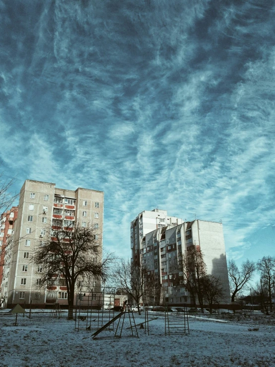 two large buildings in an open field next to trees