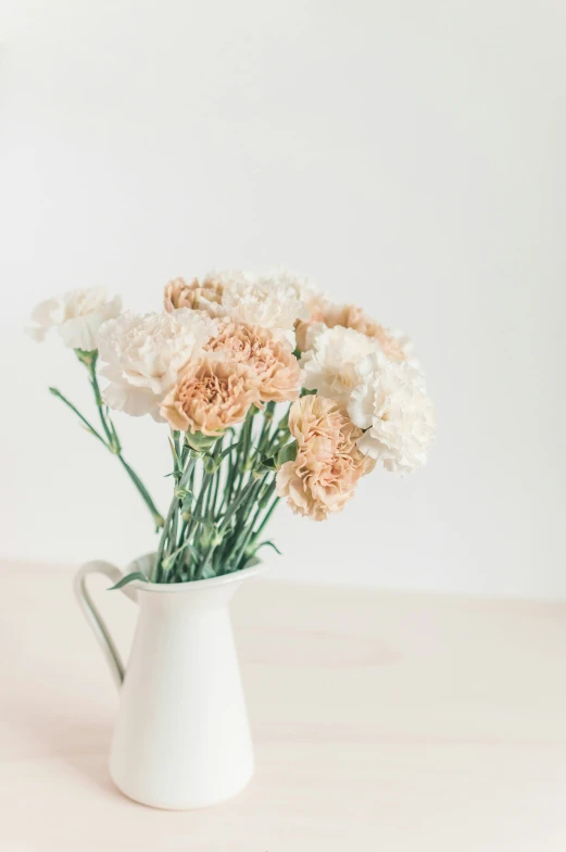 a white vase with flowers sitting on a table