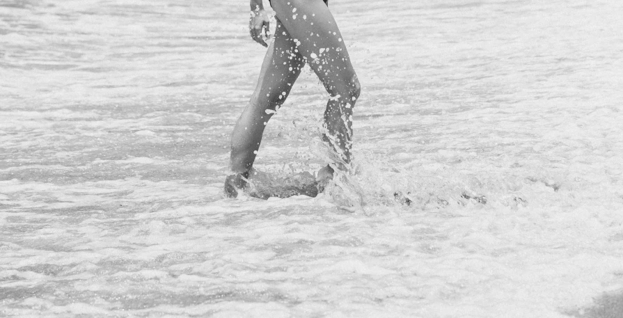 a woman in a bathing suit walking through the ocean