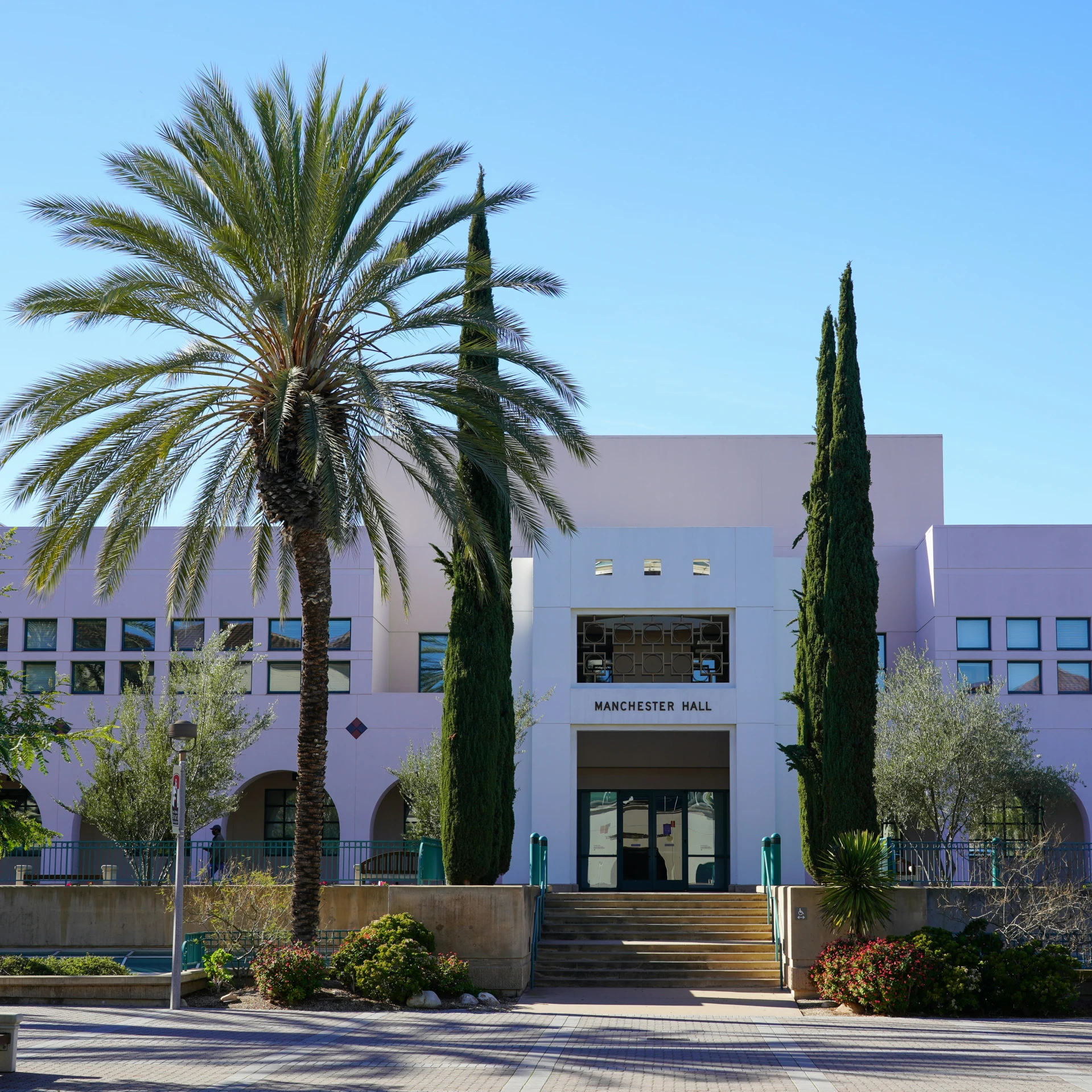 a pink building with three trees and two benches