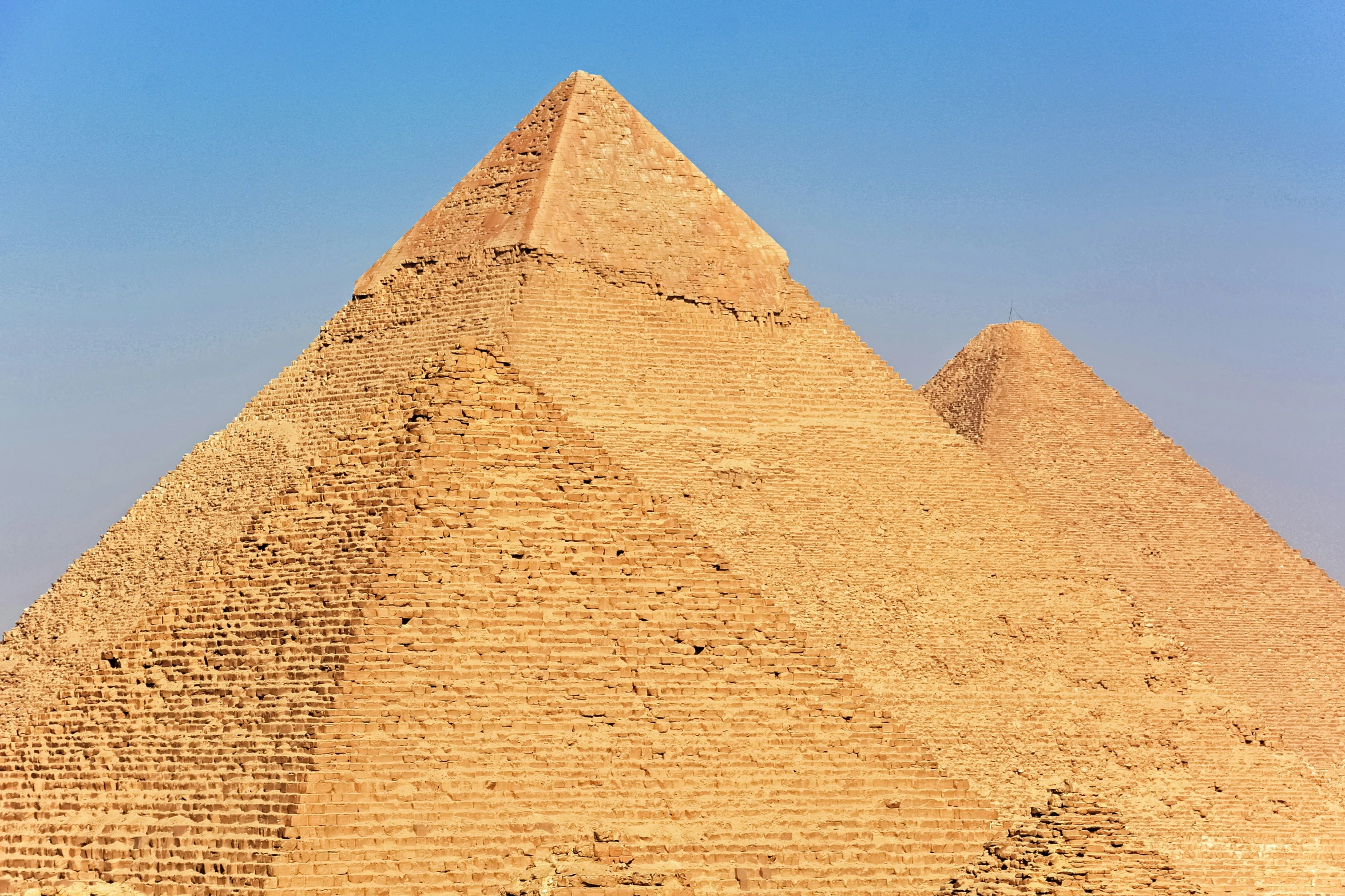 a man walks between two very tall pyramids