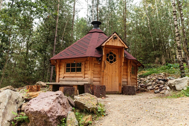 a small log cabin nestled in a forest with rocks and trees