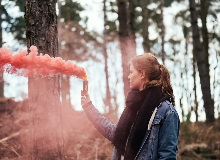 a woman blowing smoke in a forest