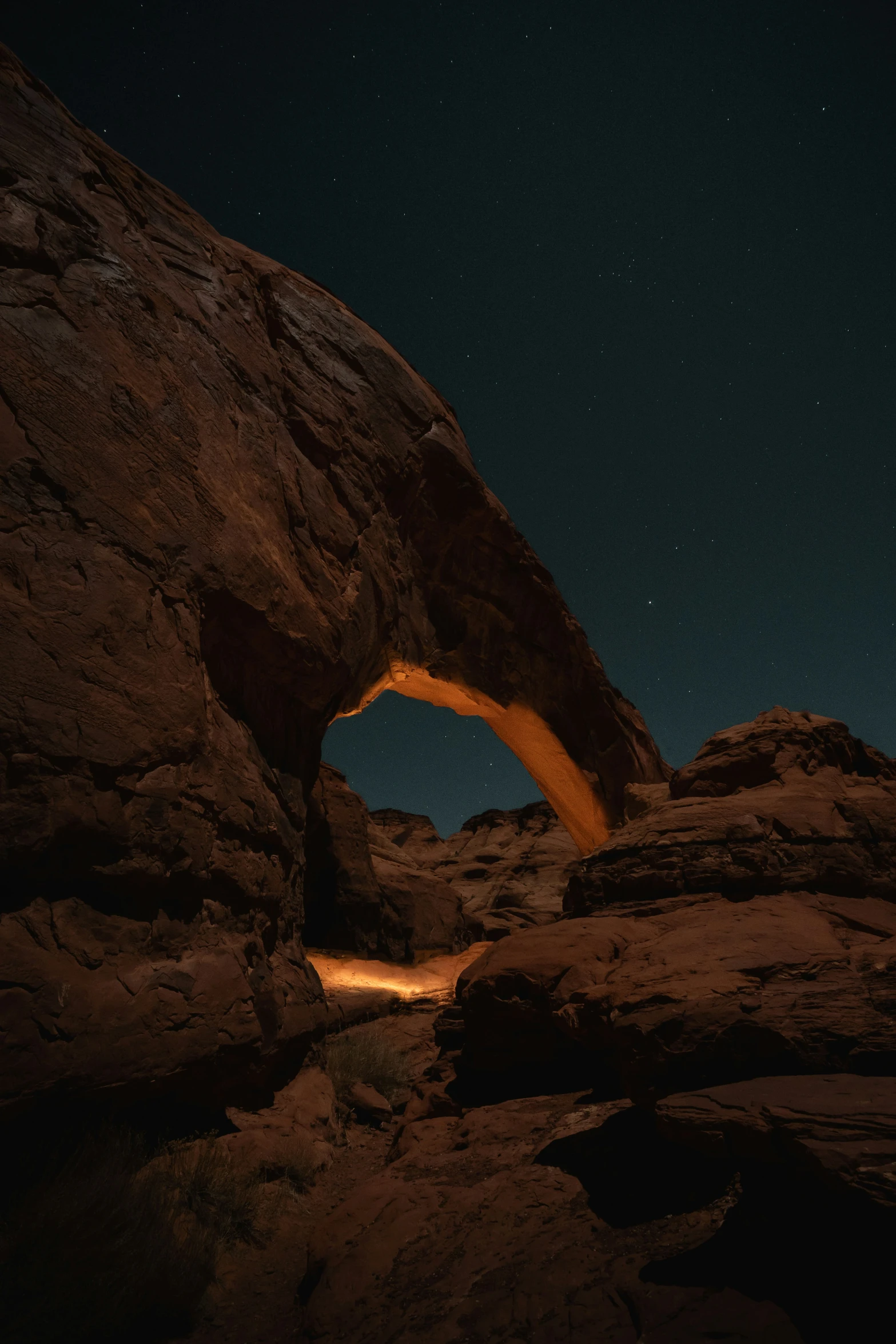 a dark night, with the moon shining behind a rock arch