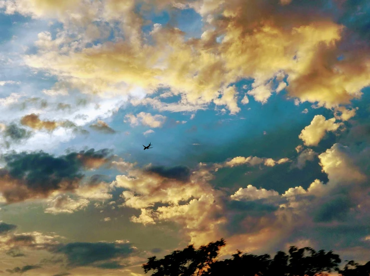 a plane flying into a cloudy sky on an evening