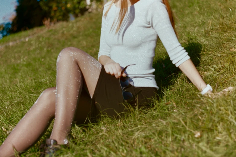 a woman wearing tight stockings sitting in the grass