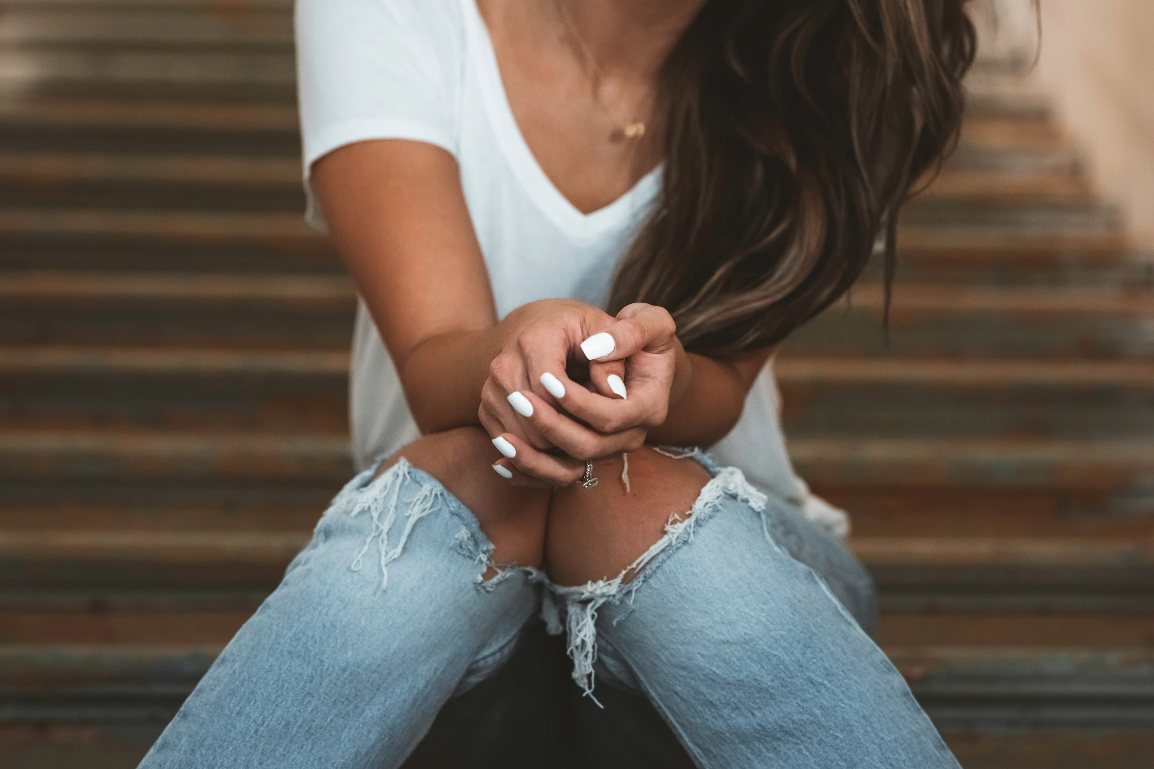 a young woman sits on a set of stairs while holding her hands together