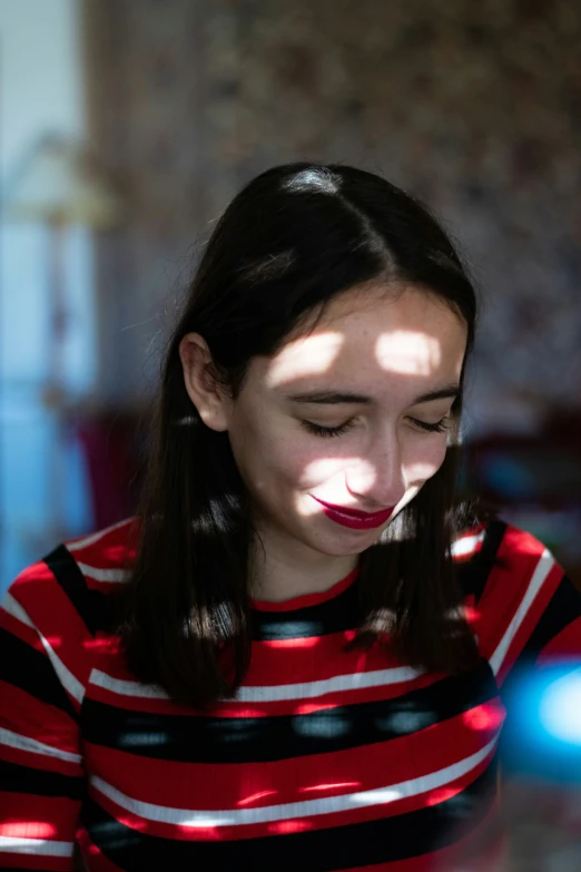 a young woman looking at her cellphone with sunlight coming through the window